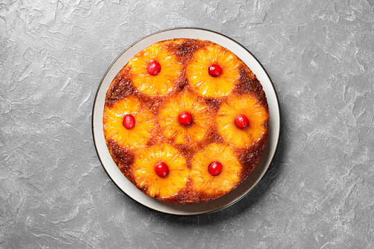 Homemade pineapple upside down pie with candied cranberry . Tropical dessert on gray stone background . 