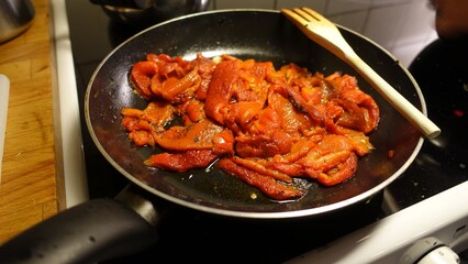 Red peppers in a pan with garlic, oil, parsley.