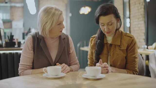 Senior woman comforting depressed friend in cafe, emotional support, problem