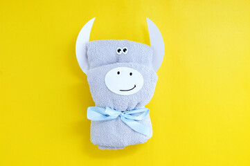 Gray terry towel folded in the form of  white bull on a yellow background.
