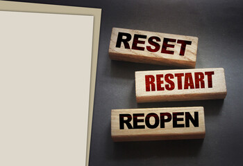 Reset, restart, reopen on wooden blocks on black . Post pandemic world concept