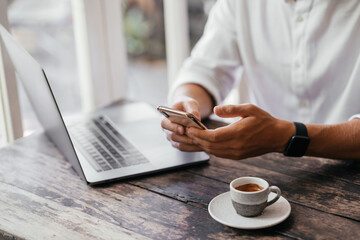 man hand use phone and laptop connecting wifi internet, sitting at wooden table in coffee shop
