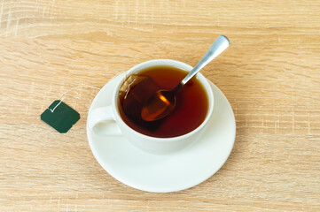 white cup with black tea, brewed tea bag in boiling water close-up, selective focus, business concept