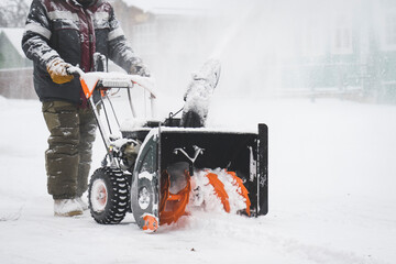 a man removes snow with a snow plow after a heavy snowfall near his house, close-up, blizzard, snow in the lens, selective focus, snow