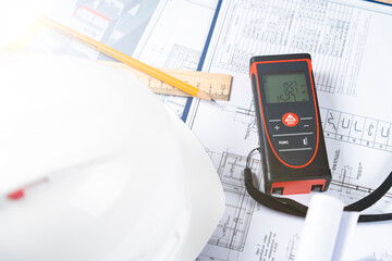 helmet and tools for construction drawings and construction drawings and laser rangefinder for distance measurements, close-up, selective focus, tinted image,