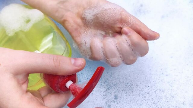 Bottles of detergents float in the foam. The concept of the dangers of household chemicals. Sodium laureate, parabens, sulfates and other chemical compounds in the foam. Liquid soap in a yellow jar