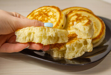 Pancakes on the table in the hand of a bitten piece, soft and airy dough