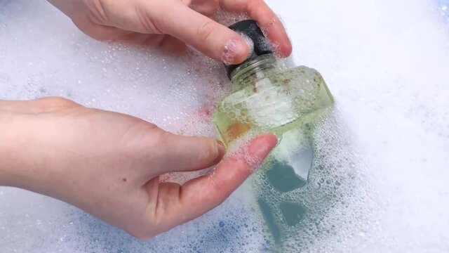 Detergent bottles float in the foam. The concept of the dangers of household chemicals. Laureate of sodium, parabens, sulfates and other chemical compounds in the composition. Mouthwash in a container