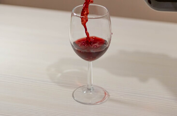 A thin stream of red wine pours into the glass