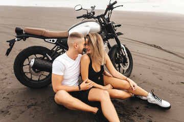 Fototapeta na wymiar Young couple riders together on sand beach by motorbike - travel concept