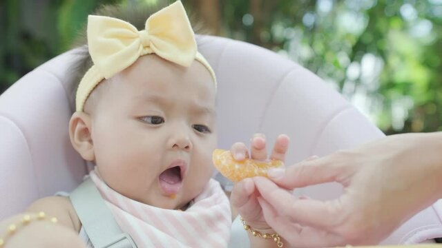 4k Baby infant daughter toddler eating on highchair in a garden