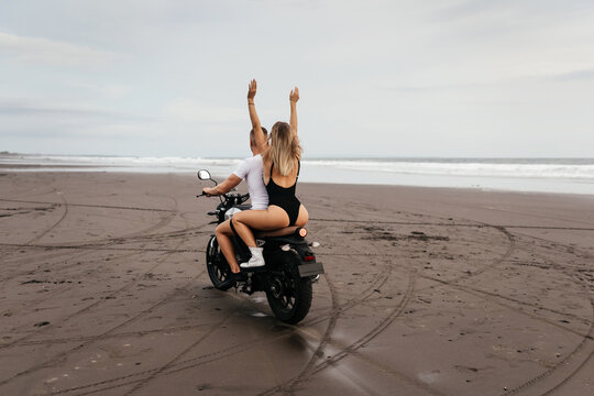 Young couple riding motorcycle on the beach, outdoor portrait, blonde girl, travel together, ocean, sea