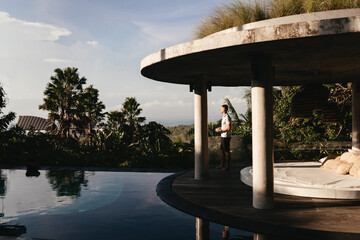 Young man using a laptop computer in a garden with a swimming pool. business, study, freelance