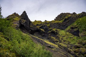 Icelandic landscape with green hills and black sands.