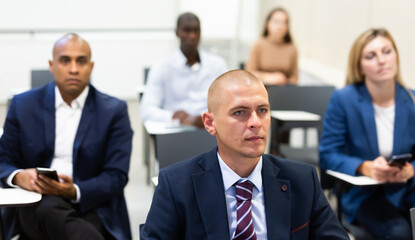 Portrait of concentrated young businessman attending business seminar in conference room