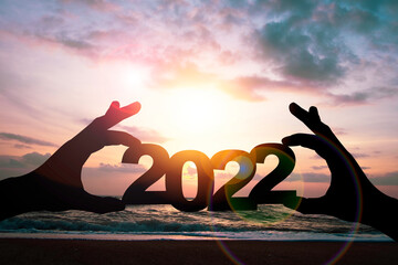 Silhouette hand holding 2022 year on beach side. Preparation happy new year to plan and starting...