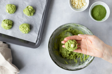matcha green tea cookie dough balls in female hand. Process of baking cookies at home. Healthy nutrition, superfoods. blurred background. top view.
