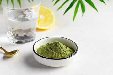 Green superfood powder for making healthy energy drink. Powder mix from wheat grass, barley grass, chlorella, spirulina, maca, matcha. White background. close-up