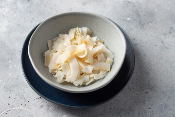 full bowl of coconut chips on gray background. Vegan snack. healthy dessert. close-up.