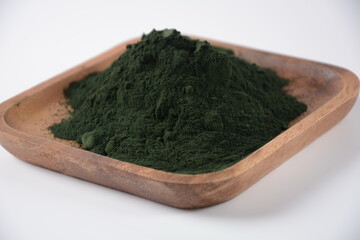 Organic green spirulina powder on wooden tray . Seaweed powder in dish bowl isolated on white background.
