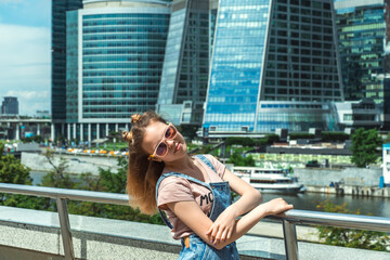 portrait of a caucasian teenage girl in sunglasses against the backdrop of an urban cityscape