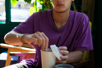 guy prepares a drink in a paper cup. young man is drinking tea.