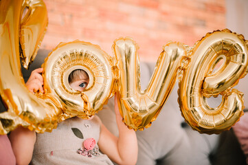 girl peeking through balloons in the form of letters love
