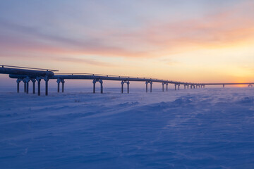 Fototapeta na wymiar Gas pipelines, pipes for gas and oil transportation, oil and gas industry, gas and oil fields in the far north, gas pipeline in winter at sunset