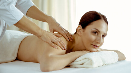 Obraz na płótnie Canvas Pretty brunette woman enjoying procedure of back massage in spa salon. Beauty concept