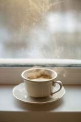 Cup of coffee on a table frosen widow