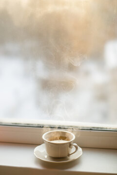 Cup of coffee on a table frosen widow