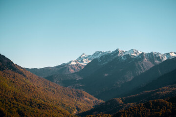 Naklejka premium Beautiful brown mountains with snow-capped peaks against a blue sky. Natural wallpaper.