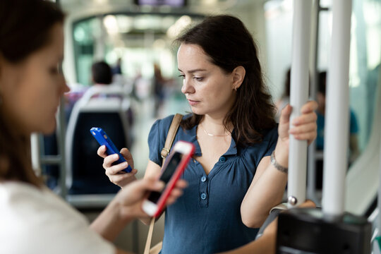 Positive woman reading from mobile phone screen in the cabin of bus or tram. High quality photo