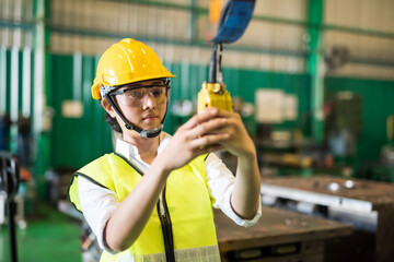 AsianfFactory worker lift crane by control panel