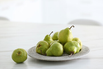 Plate with fresh ripe pears on white table