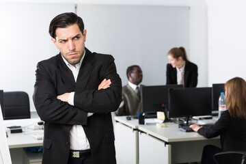 Angry manager standing in office dissatisfied with teamwork of colleagues