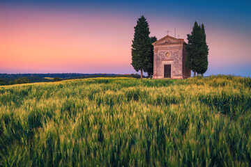 Fototapeta na wymiar Small Vitaleta chapel and grain fields at sunset, Tuscany, Italy