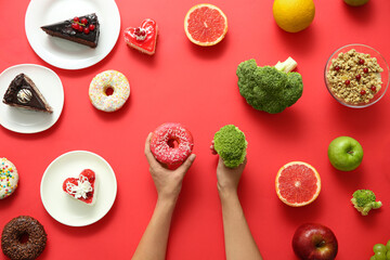 Top view of woman choosing between sweets and healthy food on red background, closeup