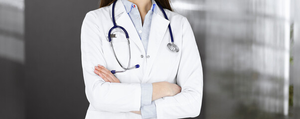 Unknown young woman doctor is standing with arms crossed in clinic. Medicine concept during...