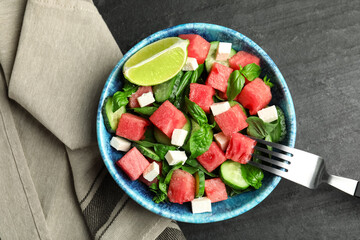 Delicious salad with watermelon served on black table, flat lay
