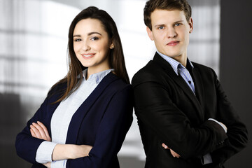 Friendly young colleagues are standing as a team with crossed arms in a modern office. Portrait of successful business people at work