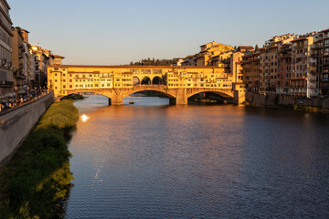 Fototapeta na wymiar a boat with tourists sails under the famous Ponte Vecchio bridge over the Arno river