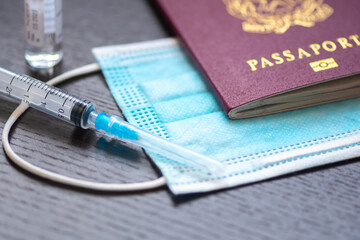 Syringe with needle, vial, surgical face mask and passport or visa on a white table ready to be...