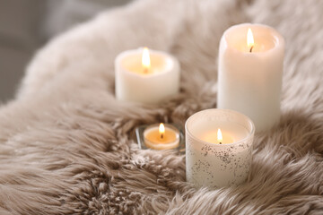 Beautiful burning candles on fuzzy faux fur rug