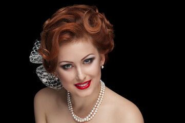 Portrait of smiling pretty red-haired lady in retro style posing on black background