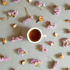 Obraz na płótnie Canvas Cup of black tea with dry flowers on gray background. top view