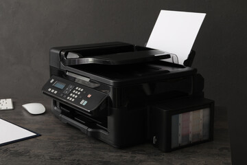 Modern printer with paper on grey table at workplace