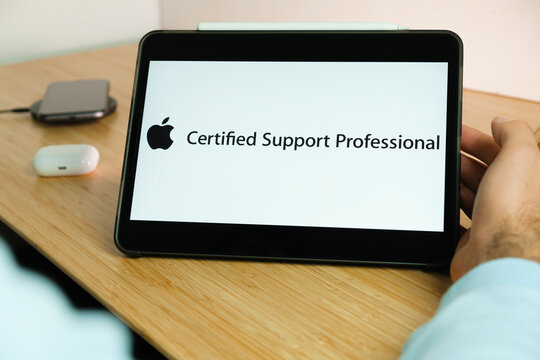 Apple Certified Support Professional ACSP logo on the screen of iPad tablet with smart phone iPhone charging on the wireless charger and airpods in the case on the background, November 2020, San