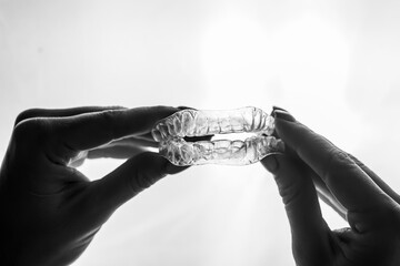 Transparent trays for correcting teeth in female hands. Removable plastic retainers