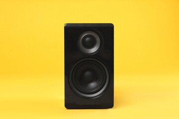 Modern powerful audio speaker on yellow background